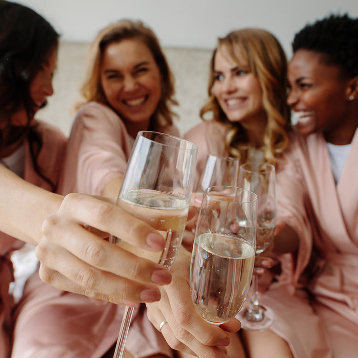 4 women in pink satin roses cheering with champagne celebrating an engagement