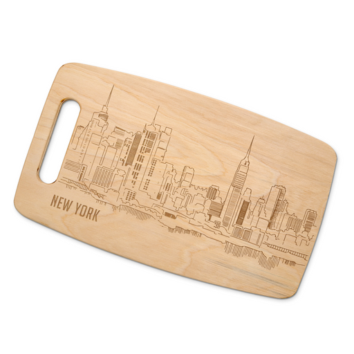 New York City skyline maple cutting board displayed on a rustic wood table with red and white gingham fabric.