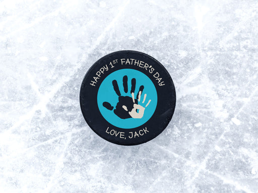 hockey puck ontop of ice with blue 1st Fathers Day handprint design with the name Jack printed on it