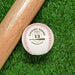 A baseball and wooden baseball bat sits on a green grassy background. The baseball has a year, player's name, number, and school name engraved into it. This design features a home plate and bat graphic with the text curved around it.