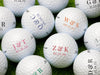 Multiple Titleist golf balls shown with different initials, dates, and colors on each ball. Golf balls sit on a grassy surface.