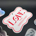 Close-up display of the “With Love” wedding gift tag in white glitter cardstock with red print. The personalized tag features custom family or sender names for wedding gifting.