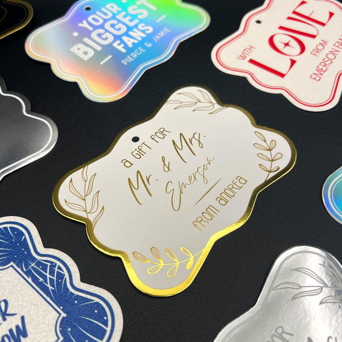 Close-up display of personalized “Mr. & Mrs.” wedding gift tags in multiple foil finishes and cardstock colors. The elegant design features custom couple names and sender personalization for weddings and bridal showers.