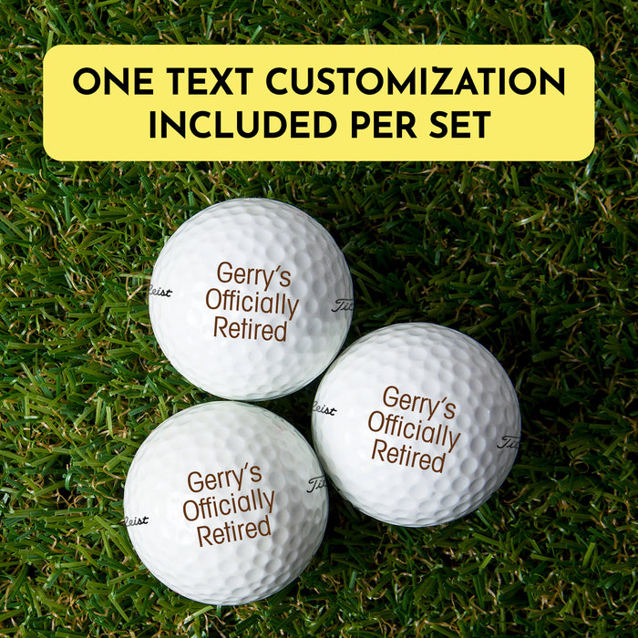 three golf balls with custom text printed on them, placed on a grassy surface.