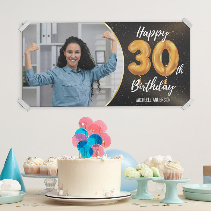 Personalized black and gold birthday banner displayed with cake and party decorations.
