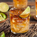 Personalized whiskey glass displayed with whiskey, ice, and fresh lime on a rustic wooden surface. The “Caleb’s Liquid Patience” engraving stands out clearly, showing how the finished custom rocks glass looks in a stylish home bar setting.