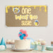 First birthday dessert table setup featuring a custom printed bee themed birthday banner displayed above a birthday cake and party decorations.