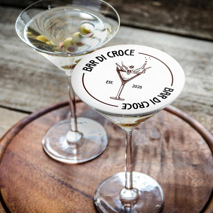 Personalized espresso martini coaster displayed beside two martini glasses on a wooden table, featuring the custom bar name, espresso martini illustration, and established year.