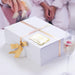 White gift box wrapped with satin ribbon and decorated using a gold foil “Let Love Sparkle” wedding gift tag. Styled as premium wedding gift packaging for bridal showers and receptions.
