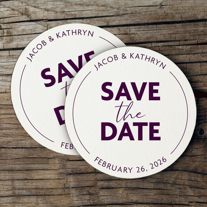 Custom Save the Date coasters displayed on a rustic wood background. Features a modern circular design with custom names and wedding date.