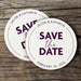 Custom Save the Date coasters displayed on a rustic wood background. Features a modern circular design with custom names and wedding date.
