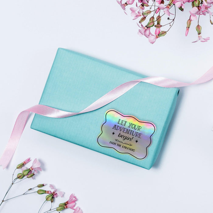Small pastel gift box wrapped with ribbon and finished using a rainbow foil “Let Your Adventure Begin” wedding gift tag. A colorful and modern packaging idea for weddings and favors.