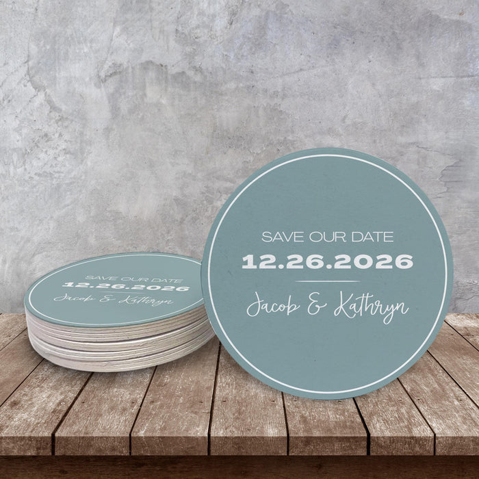 Custom Save the Date coaster displayed on a rustic wood surface. Features a clean modern layout with custom names and date.