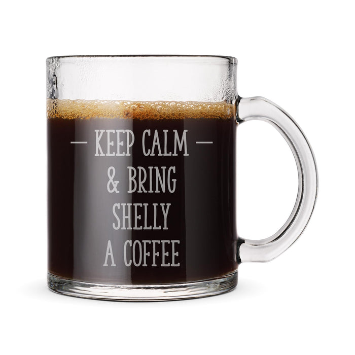 A clear glass mug filled with coffee, with the text "KEEP CALM & BRING SHELLY A COFFEE" engraved on it.