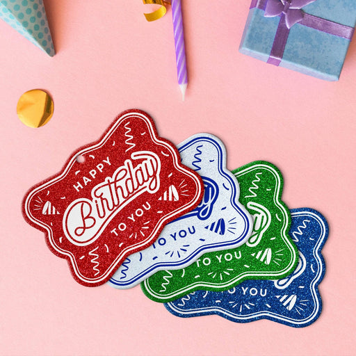 Four birthday rectangle tags in glitter blue, glitter red, glitter green, and glitter white.