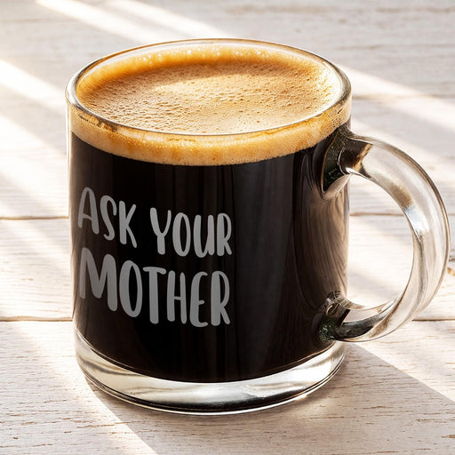Glass mug filled with coffee topped with light foam featuring the “Ask Your Mother” engraved design. A simple lifestyle image showing the mug as a daily coffee companion.