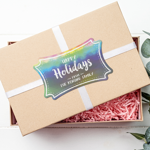A brown gift box with a white ribbon and a rainbow gift tag that says "Happy Holidays".