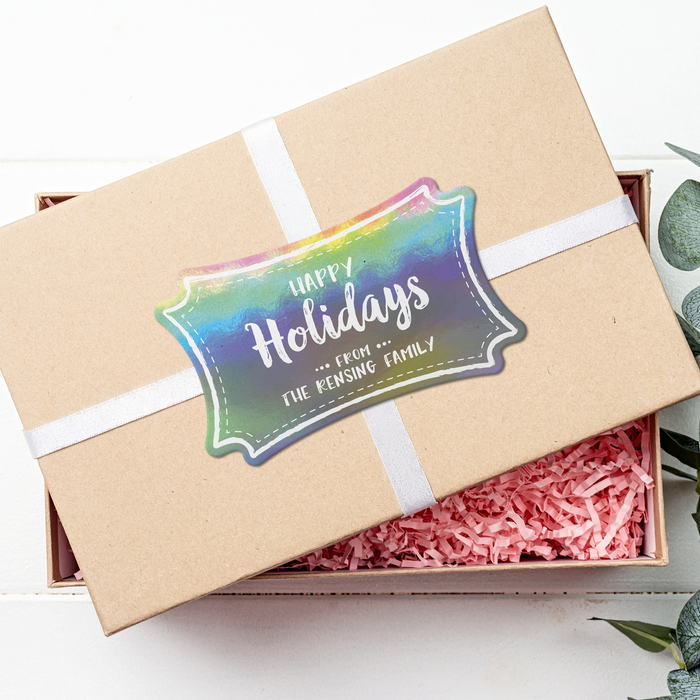 A brown gift box with a white ribbon and a rainbow gift tag that says "Happy Holidays".
