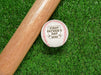 Baseball sits on grass next to baseball bat. Baseball has First Father's Day design engraved on it.