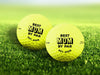 Two yellow golf balls with Best Mom By Par design printed on them, placed on a grassy golf course.