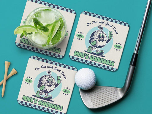 Custom square pulpboard coasters are shown sitting on a teal surface. Golf tees, a golf ball, and a golf club sit beside them. One coaster has a cocktail on top of it. The custom coasters feature a retro design printed with blues and a mint green with an illustration of a fun, rubberhose style golf ball character and a checkered border on the top and bottom of the coasters.