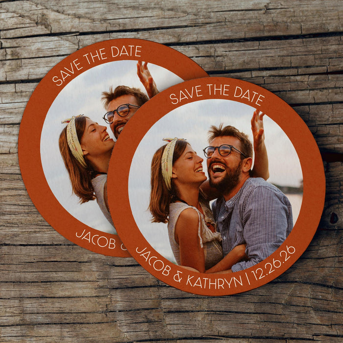 Stack of custom photo Save the Date coasters displayed on a rustic wood background. Personalized with a photo, names, and wedding date.
