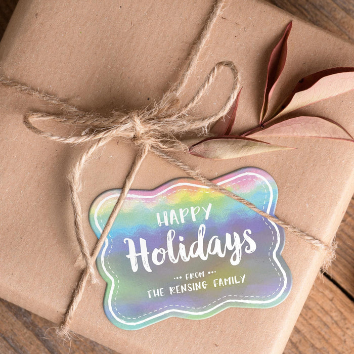 Personalized rounded rectangle Christmas gift tag placed on a kraft paper wrapped gift tied with natural twine and dried leaves.
