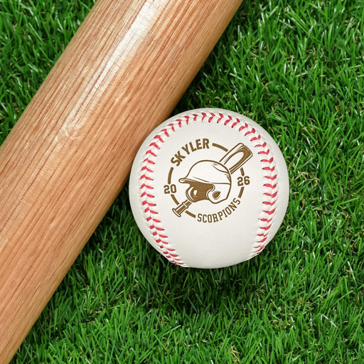 A baseball bat and a personalized baseball resting on a grassy surface.