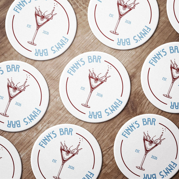 Multiple round martini coasters arranged together, each featuring the personalized bar name, martini glass design, and established year.