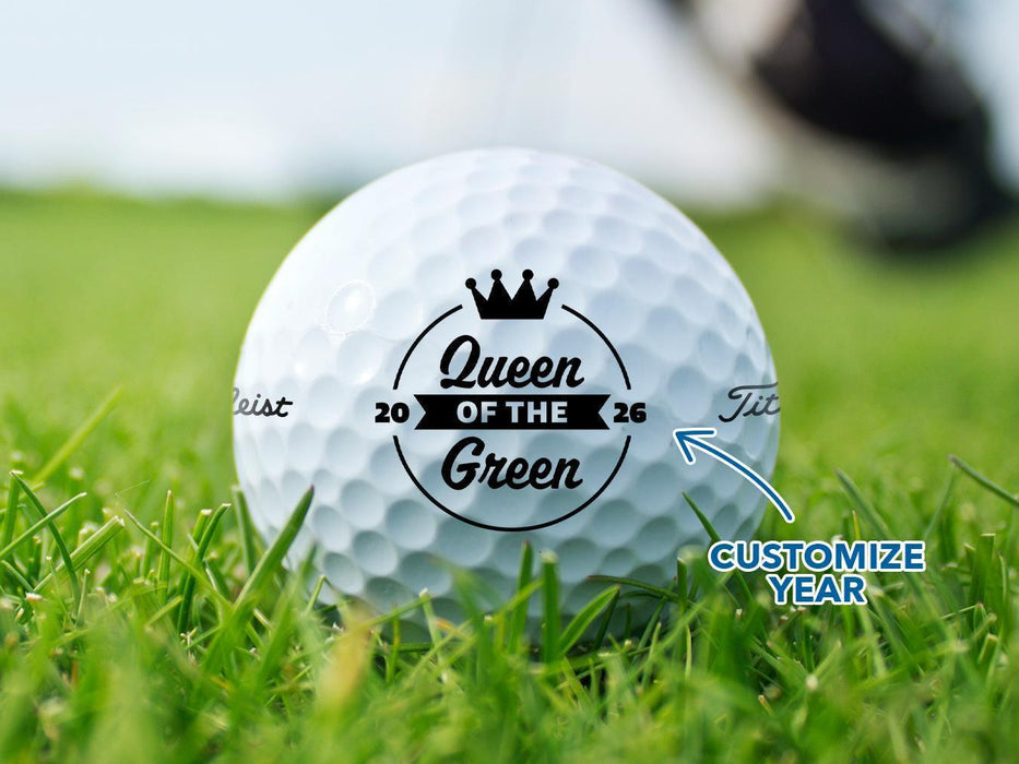 A close-up of a golf ball with a crown and the text "Queen of the Green", surrounded by grass, with text indicating that the year can be customized.