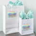 White gift bags with tissue paper decorated using personalized “Let Love Sparkle” holographic foil wedding gift tags. Perfect for wedding welcome bags, favors, and bridal party gifts.