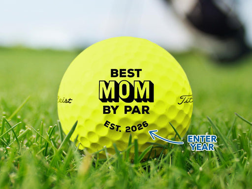Custom yellow Callaway golf ball shown with a Best Mom By Par design printed on it. The golf ball sits on a grassy golf course.