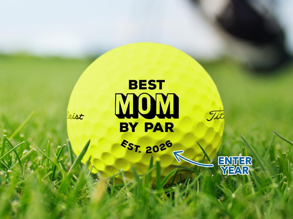 Custom yellow Callaway golf ball shown with a Best Mom By Par design printed on it. The golf ball sits on a grassy golf course.