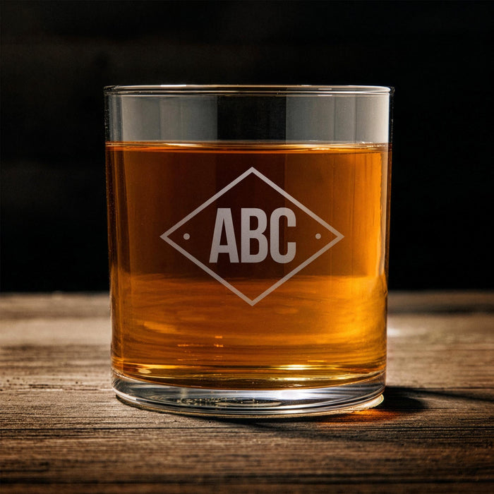 Front-facing product image of the whiskey glass on a wooden surface, showcasing the diamond initials layout for easy visualization of personalization.
