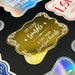 Close-up display of the personalized “Let Love Sparkle” wedding gift tag in gold foil with decorative flourishes and custom sender names. Styled as an elegant keepsake tag for weddings and bridal showers.
