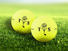 Two personalized yellow golf balls with a Floral Initial Monogram design printed on them, placed on a grassy field.