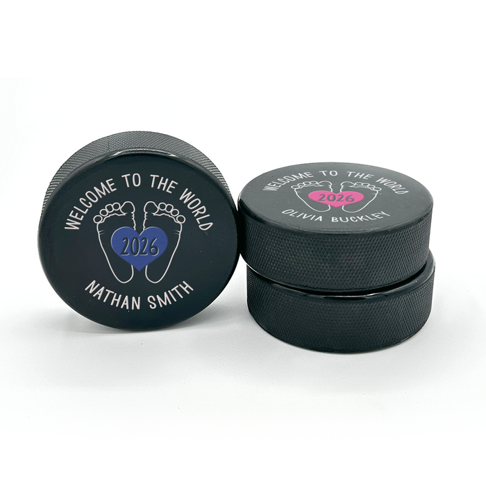 Two personalized hockey pucks showing the UV printed “Welcome to the World” birth announcement design from the front and side.
