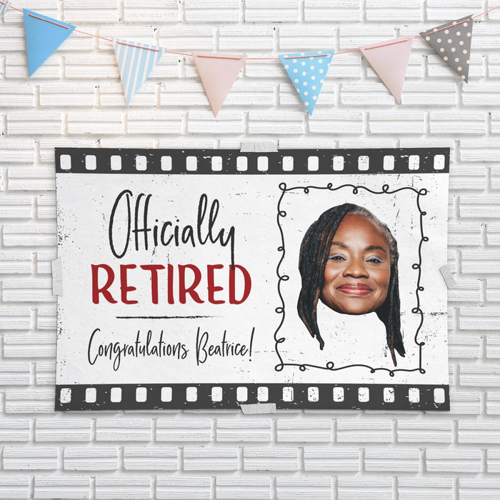 Officially Retired retirement banner displayed against a white brick wall backdrop. Personalized retirement party decoration with custom photo and congratulatory message.