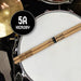 A pair of drumsticks with the text "Happy Birthday" engraved on them, placed on a drum set.