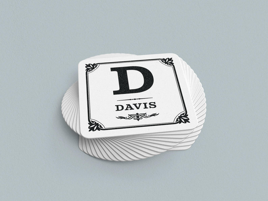 Stack of coasters sit on a gray background. Coasters say Davis with decorative frame.
