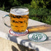 Personalized football coasters shown outdoors with a beer mug, featuring custom team wording and family names.