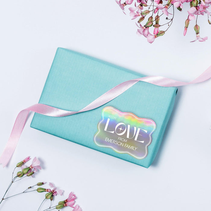 Small pastel gift box wrapped with ribbon and decorated using a personalized “With Love” foil wedding gift tag in holographic rainbow foil. A colorful and elegant touch for wedding favors and gifts.