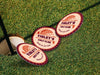 Three custom round pulpboard coasters are shown falling onto golf course. The custom coasters feature design printed with bold golf imagery, striped radial border, and custom text.