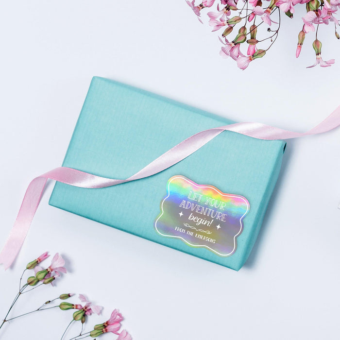 Pastel blue envelope with ribbon accented by a holographic rainbow “Let Your Adventure Begin” personalized wedding gift tag. A colorful and modern wedding stationery presentation.