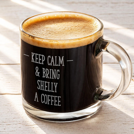 A mug of coffee with the text "KEEP CALM & BRING SHELLY A COFFEE" engraved on it.