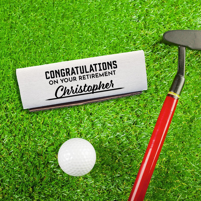 A white gift box for a single golf ball sleeve with a personalized printed message. This box is shown next to a golf club and a golf ball on a grassy surface.