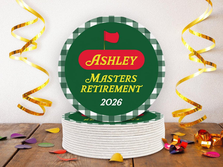 A stack of custom pulpboard coasters are shown sitting on a wooden table surrounded by colorful confetti. The coasters read Ashley Masters Retirement 2026. These feature a red, green, and yellow Masters-themed retirement party design with the retiree’s name and retirement date.