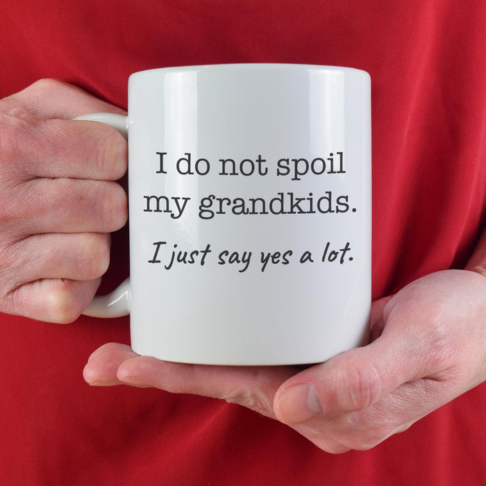 Funny grandparents mug held in hand with “I Do Not Spoil My Grandkids. I just say yes a lot. ” saying.