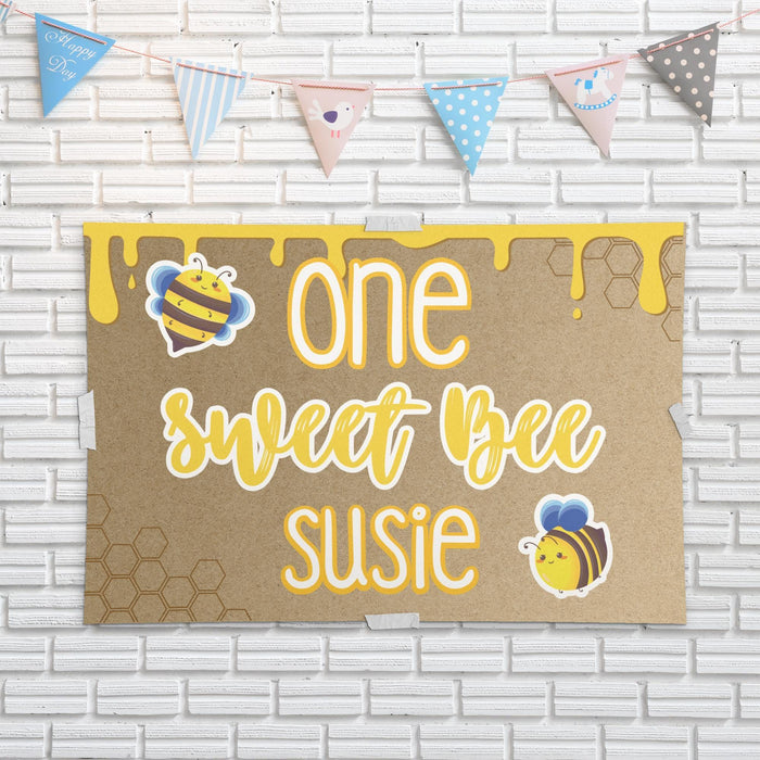 One Sweet Bee birthday backdrop displayed against a white brick wall showing the printed butcher paper material and playful bee theme design.