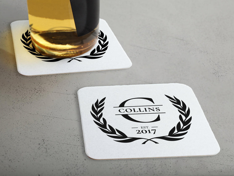 One coaster has a drink on it and an empty coaster sits beside it. Coasters say Collins Est. 2017 with laurel design.